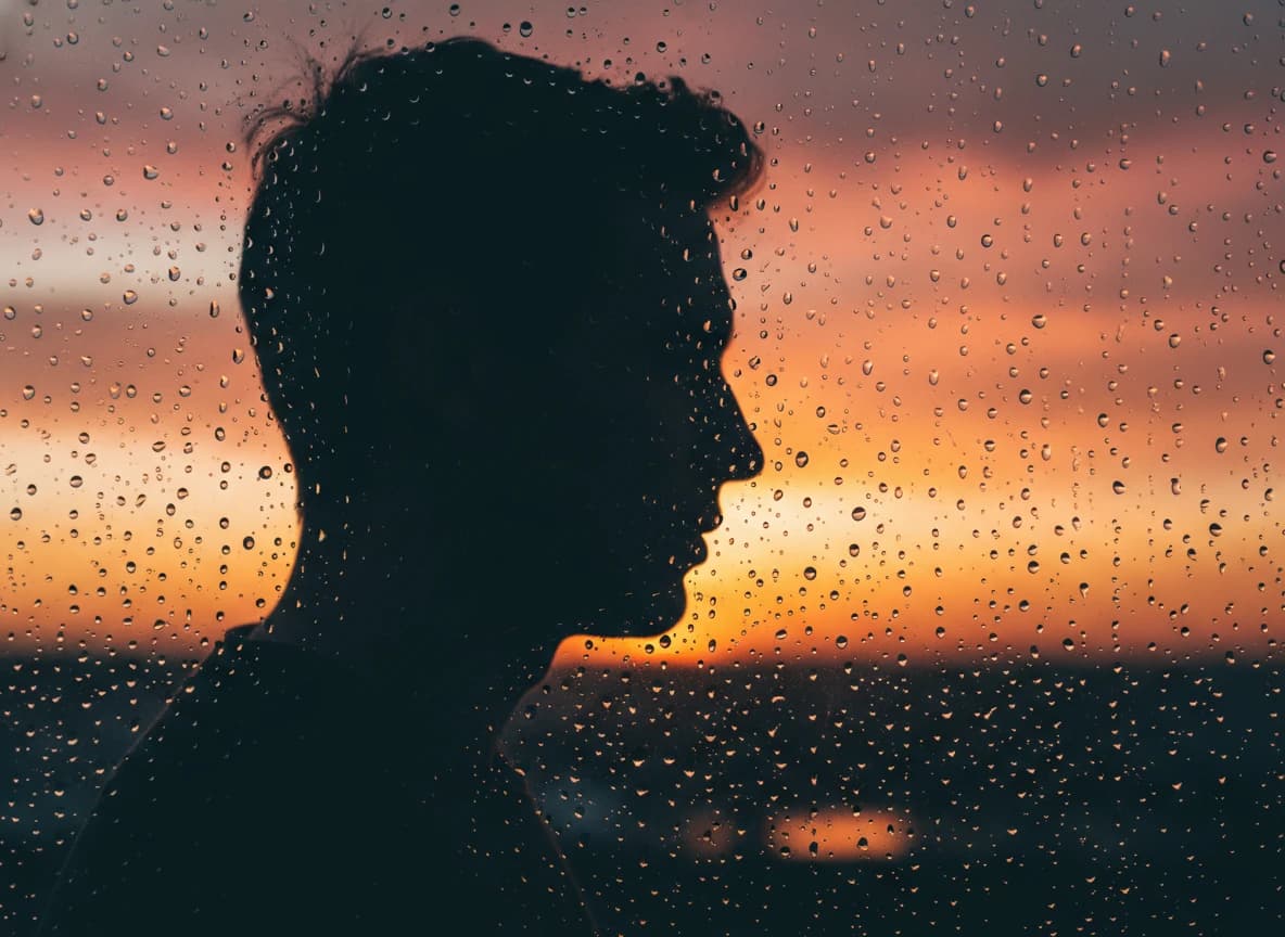 Silueta al atardecer tras cristal mojado — prompt generado con IA