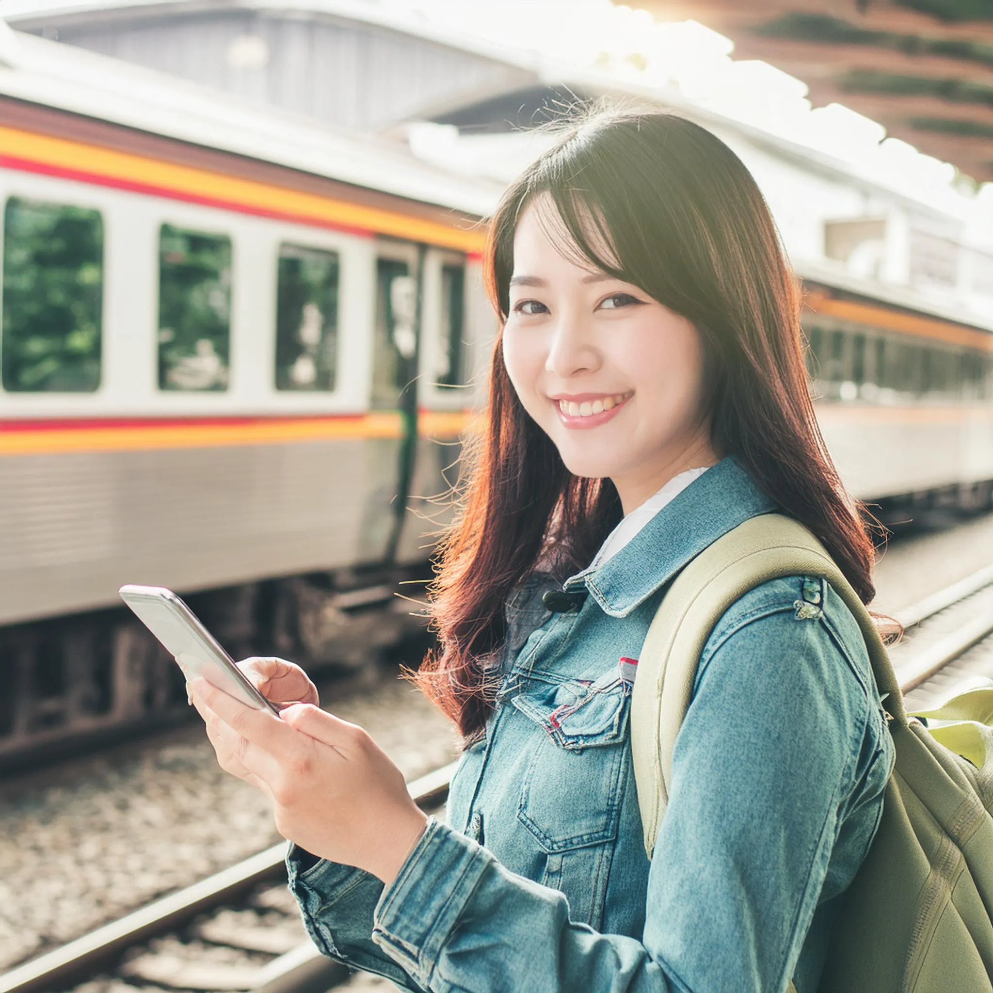 スマートフォンを見て笑顔の学生。女性。電車